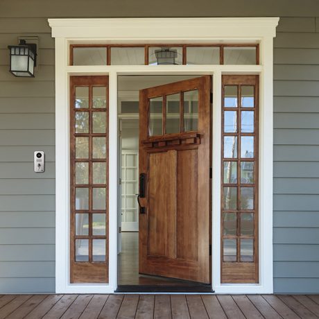 Wooden door with silver Doorbird video doorbell on left side of porch