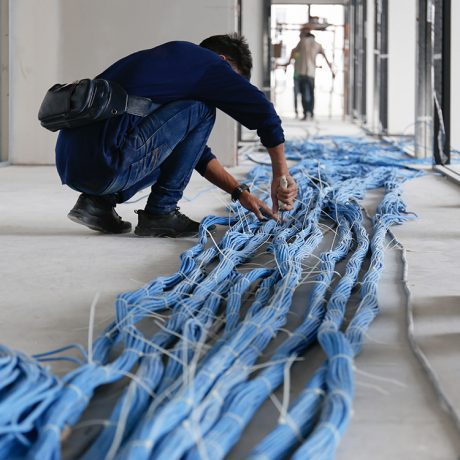 Worker wiring LAN cable at construction site. Unfinished Installation network system.